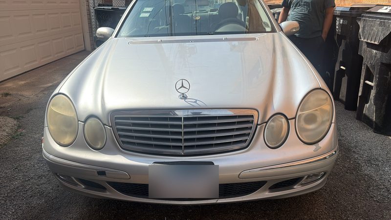 Silver Mercedes-Benz E-Class sedan bought for cash for junk cars, waiting for pickup in a Chicago alley behind a garage